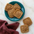 Cookies made with the Nordic Ware Fall Forest Springerle Cookie Stamps on a teal plate next to a burgundy linen towel