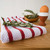 The Now Designs Red Stripe Dish Towel with rosemary on a counter
