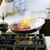 A fry pan from the Heritage Steel Titanium Series 5 Piece Fry Pan Set being used to flambe fruit