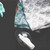 Two of the Now Designs Dust Bunny Dish Cloths in a basket next to a spray bottle