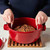 A person starting to lift a loaf out of a Dutch oven with the King Arthur Baking silicone round loaf lifter