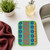 A Wet-It! Skrubba XL Scratch-Free Scrub Pad next to a kitchen sink, ready to scrub dishes.