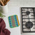 A Wet-It! Skrubba XL Scratch-Free Scrub Pad next to a gas cooktop, ready to clean tough messes.