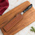 A Messermeister 8.5 Inch Magnetic Leather Edge Guard in saddle brown protects the blade of a knife with a black pakkawood handle.