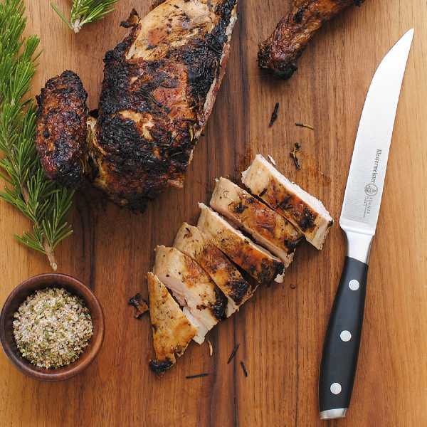 The Messermeister Avanta Steak Knife Set on a cutting board with roasted chicken