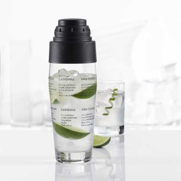 A Trudeau glass cocktail shaker filled with lime wedges ice and a cocktail