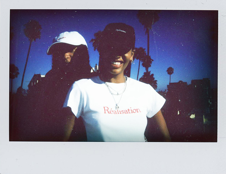 Realisation Logo Tee, White Baby Tee with Red Logo