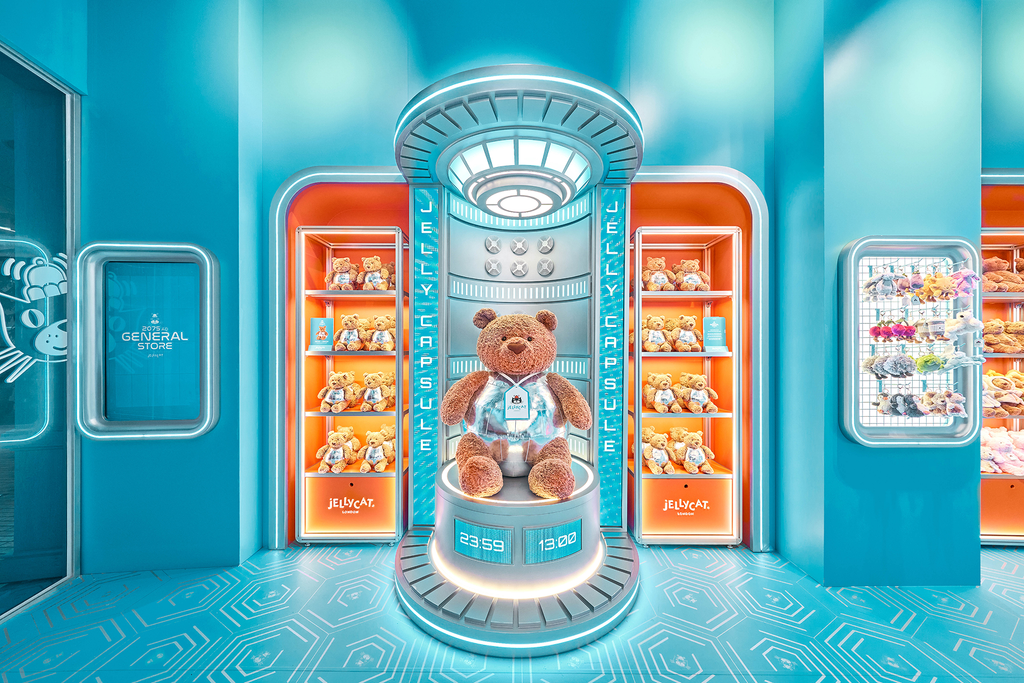 Jellycat Hyundai General Store Bartholomew Bear sits inside a glowing capsule display surrounded by shelves of plush toys in a futuristic store.