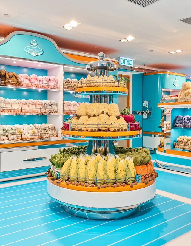 Jellycat Amuseables Vegetables and Bashful Bunnies are displayed on circular shelving inside Jellycat Yacht Club.acht Club retail display filled with plush toys, lifebuoys, and nautical-themed decor.
