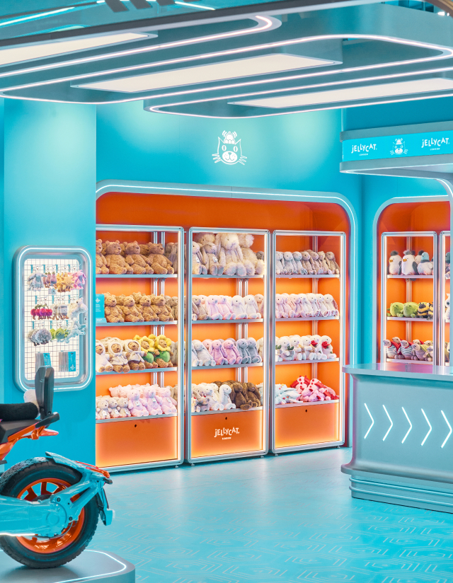 Jellycat store interior shows illuminated shelving filled with plush toys against orange and turquoise walls.
