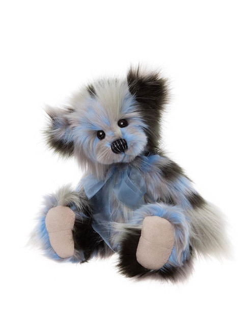 A multicoloured plush teddy bear with blue, grey, black, and white fur sits upright, wearing a sheer blue ribbon bow, against a white background.