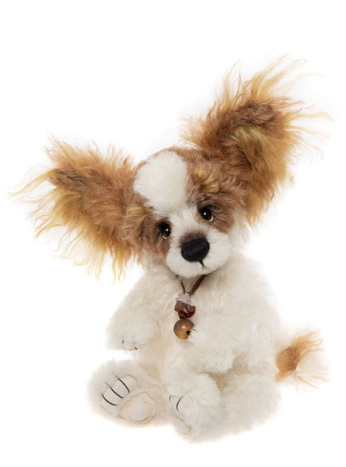 A white and brown fluffy dog-shaped Charlie Bear plush toy sits upright against a white background, wearing a small brown bead necklace, with large tufted ears.