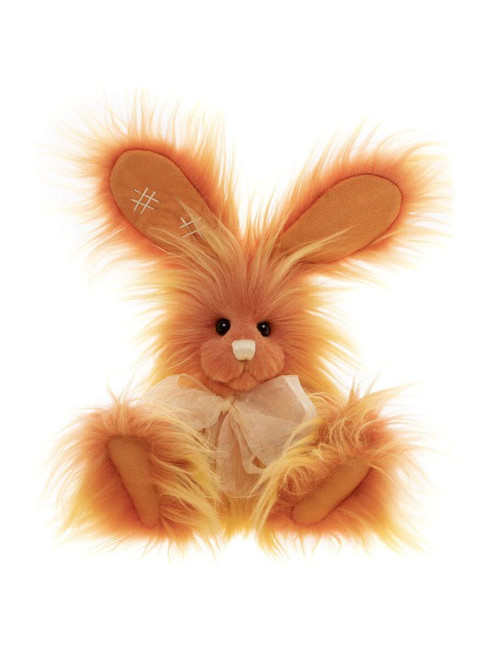 An orange fluffy Charlie Bears bunny rabbit plush toy sits upright against a white background, featuring long ears, shaggy fur, black eyes, and a cream organza bow.