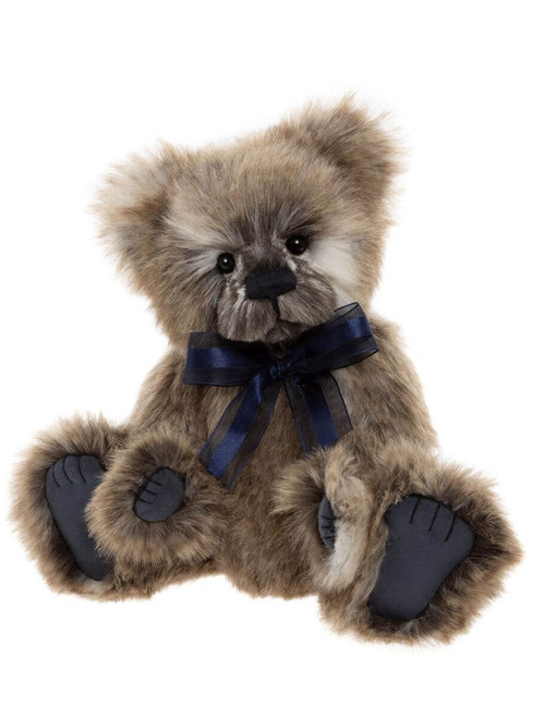 A fluffy brown teddy bear sits upright against a white background, wearing a navy blue satin ribbon bow tied around its neck, with matching dark blue paw pads.