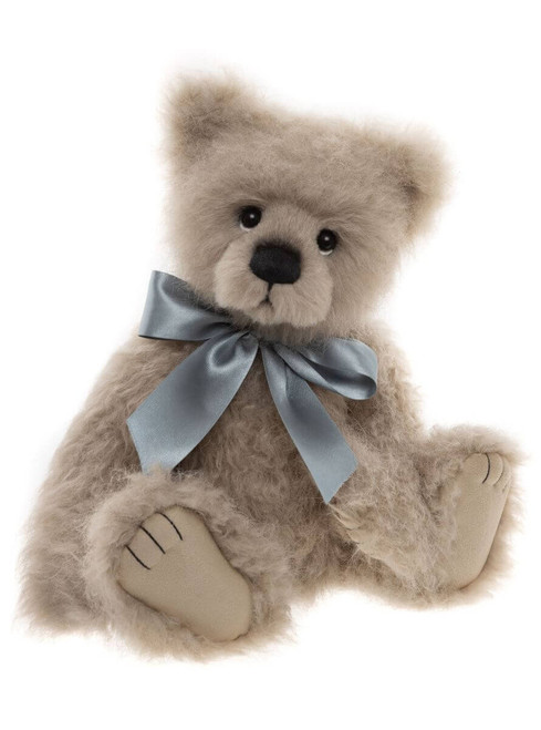 A light beige/grey mohair teddy bear sits upright against a white background, wearing a satin blue-grey bow tied around its neck.