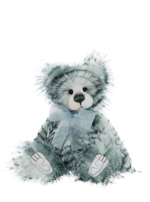 A blue-grey and white marbled fur teddy bear sits upright against a white background, wearing a sheer pale blue ribbon bow at its neck, with embroidered paw pads visible.