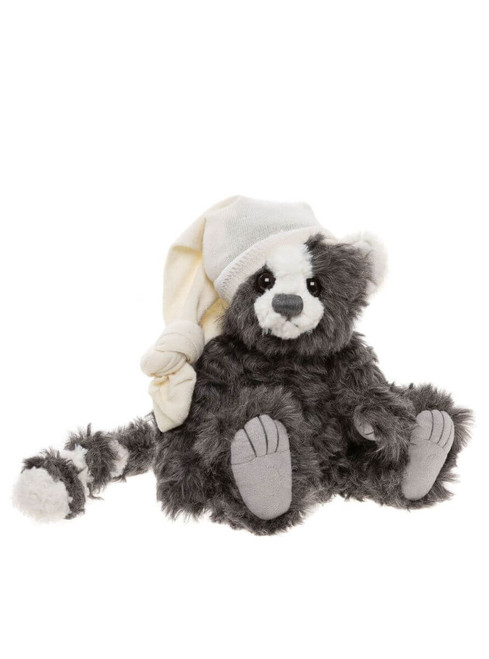 A grey and white fluffy Charlie Bears teddy bear sits upright, wearing a cream knitted nightcap and matching mittens, with grey paw pads visible on outstretched feet.