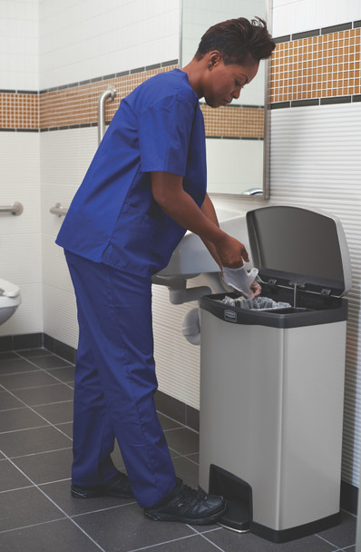 1901999 - A worker wearing blue scrubs discards of gloves using the Slim Jim pedal bin in a washroom