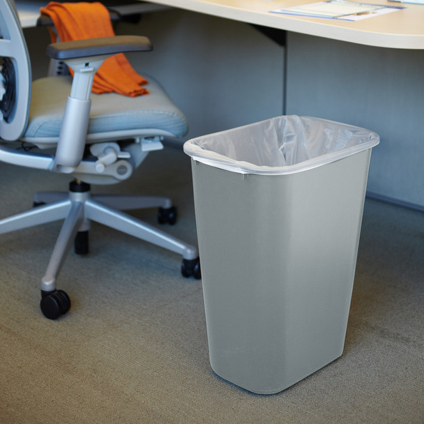 FG295700GRAY - Grey Rubbermaid wastebasket placed underneath a desk and fitted with a polythene bin liner