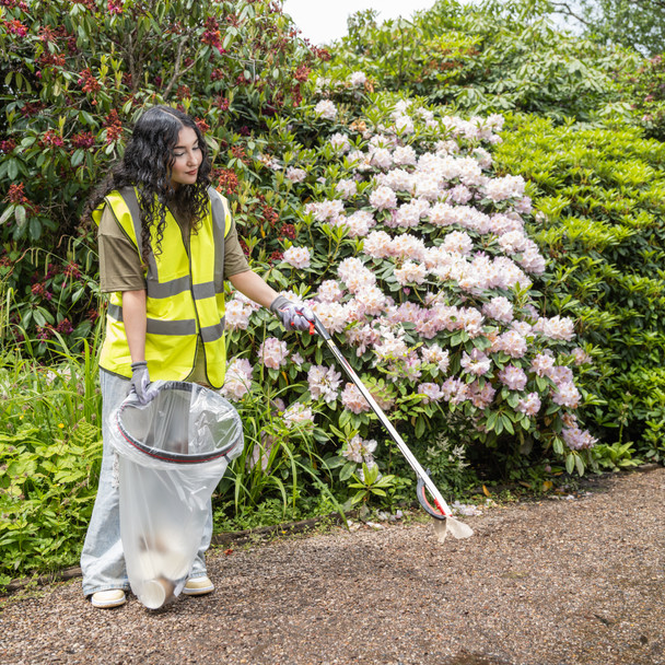 A Female Wearing High-Vis Vest, Gloves and Using a Litter Picker Collects Rubbish While Holding a Handi-Hoop