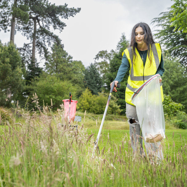Female in Hi-Vis Vest Collecting Litter from Long Grass Using the Community Litter Picker while Holding a Handi-Hoop