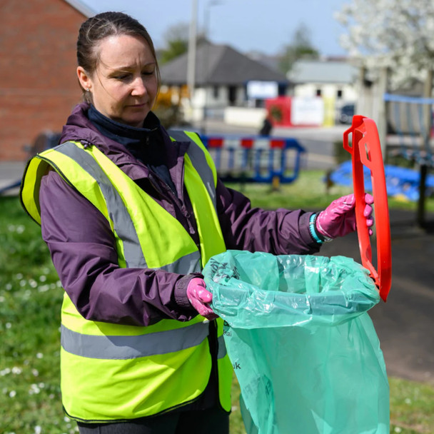 A lady wearing a hi-vis vest demonstrates the hinged rim with clip system for securing liners
