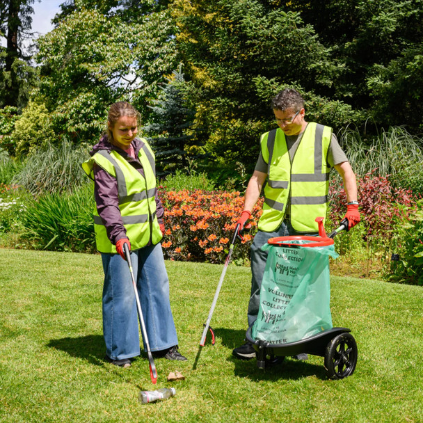 Two people - one man & one woman - wearing hi-vis vests collecting litter using pickers and the Handicart Lite
