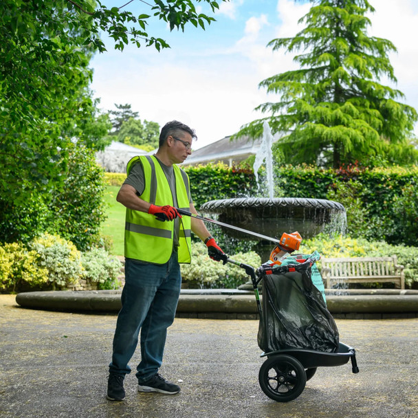 A man wearing a high-vis vest discards rubbish into a Handicart Duo fited with a black and green bin bag with a litter picker