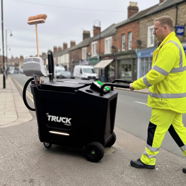 Ecogum Motorised Gum & Litter Removal Truck Being on a Town Street by a Man Wearing High-Vis Overalls