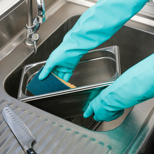 Person wearing blue gloves using a Sponrex 74 Large Sponge Scourer to clean a Gastronorm Pan