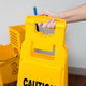 FG611477YEL - Rubbermaid 4-Sided "Caution" Safety Sign - 96.5cm - Yellow - Being Carried by Carry Handle