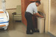 1883458 - A hospital worker wearing light blue t-shirt, black trousers and black shoes uses the bin in a patients room