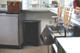 1883613 - A black Rubbermaid Slim Jim Front Step Pedal Bin situated under a counter in a bar