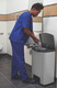 1901999 - A worker wearing blue scrubs discards of gloves using the Slim Jim pedal bin in a washroom