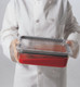 20CWGL135 - Chef in whites holds food pan that is sealed with GripLid and contains tomato sauce at an angle