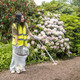 A Female Wearing High-Vis Vest, Gloves and Using a Litter Picker Collects Rubbish While Holding a Handi-Hoop