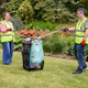 A lady and a man wearing high-vis vests discard of litter into a the black & green bin bag attached to a Handicart Duo