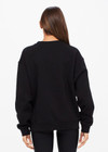 THE UPSIDE women's black Saturn Arrow Sweater is an organic cotton fleece jumper with a relaxed, oversized fit. It features a soft rib at the neckline, handcuffs and cuffs.
