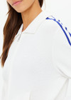 THE UPSIDE women's white Carnaby Pari Zip Knit Jacket is a zip through sports jacket with knitted blue stripes down the sleeves and welt pockets. Designed for walking and recovery.