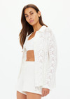 THE UPSIDE women's white Lavalliere Malia Knit Shirt is made from organic cotton. The long sleeve knit shirt features an open lace knit construction with bow knitted detailing and fitted with buttons and a ribbed collar. Designed leisure and recovery.