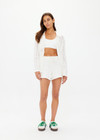 THE UPSIDE women's white Lavalliere Malia Knit Shirt is made from organic cotton. The long sleeve knit shirt features an open lace knit construction with bow knitted detailing and fitted with buttons and a ribbed collar. Designed leisure and recovery.