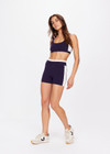 THE UPSIDE women's navy Montage Rory Scoop Crop is a knitted cropped sports bra with a scooped neckline and cream side panels for style and soft elastic underbust for comfort. Designed for light movement and recovery.