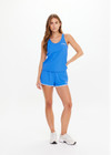 THE UPSIDE women's bright blue Wrangler Issy Racerback Tank Top is made from recycled mesh fabrication and features a curved hem.