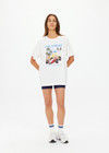 THE UPSIDE women's cream organic cotton Raceway Sammi Tee is designed for an oversized fit with printed raceway graphics on the front.
