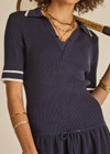 THE UPSIDE women's navy tennis Plume Knit Collared Dress fits true-to-size and features a drop waist with gathered skirt and a drawcord with tennis charms.