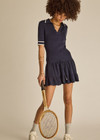 THE UPSIDE women's navy tennis Plume Knit Collared Dress fits true-to-size and features a drop waist with gathered skirt and a drawcord with tennis charms.