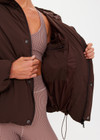 THE UPSIDE women's brown Mercer Hooded Puffer Jacket is fully lined and features invisible zip pockets with fleece lining, soft elasticated cuffs, a hood and is made from recycled fabric. Made for lifestyle.