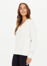 THE UPSIDE women's white Seymour Knit Sweater made with 100% organic cotton cable knit fabrication features a v-shaped neckline, ribbed cuffs, hem and neck, and embroidered arrow logo on back of neck.