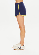 THE UPSIDE Bamford Callie Short in Navy is a sustainable organic cotton mid-rise mini 70s inspired jogger short with pockets, elasticated waist, contrast rib bind down side seam and hem and embroidered with our varsity TU patch.