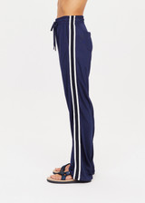 THE UPSIDE womens navy mid rise Celeste Pant made with slinky fabrication features a relaxed straight leg silhouette, elasticated waistband, drawcord, and white stripe down side seams.